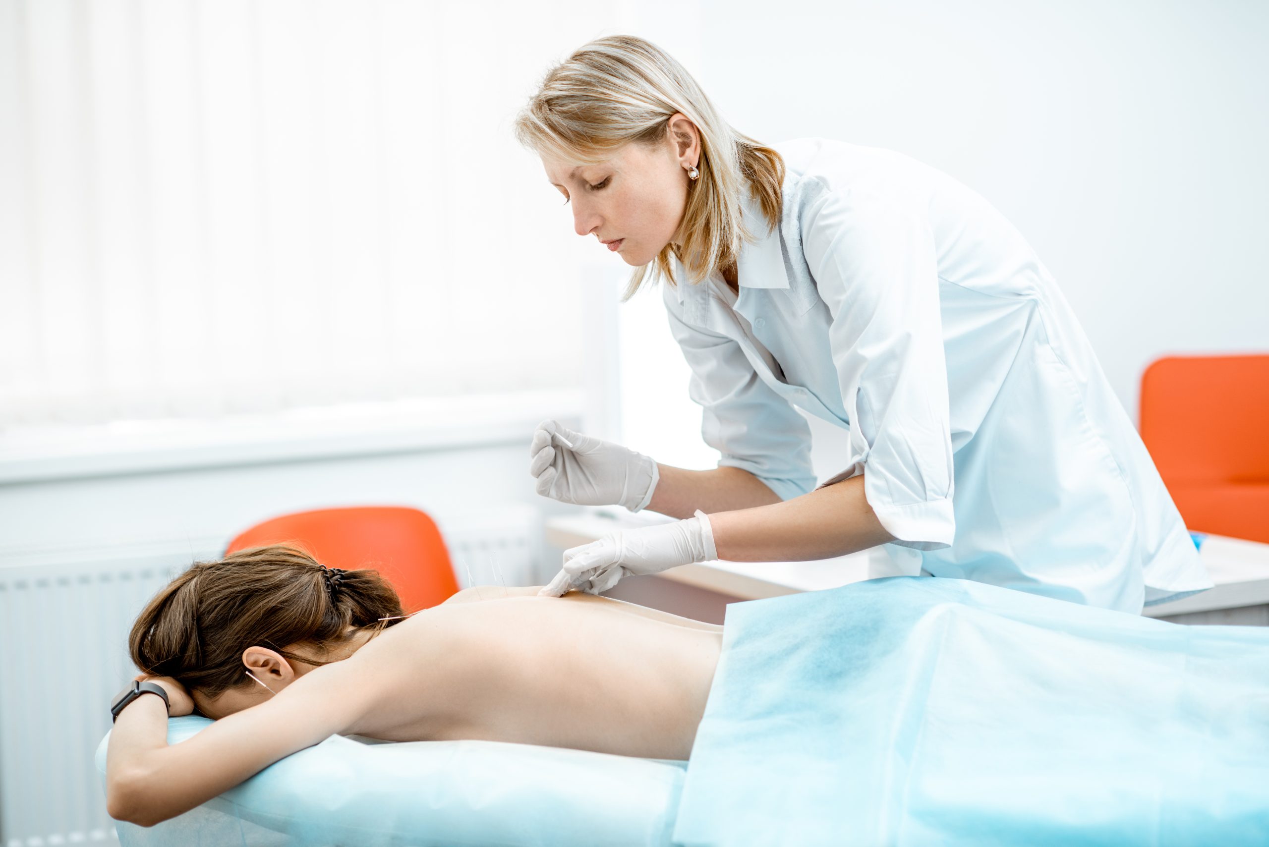 Profesional sanitario realizando un tratamiento de acupuntura a una paciente