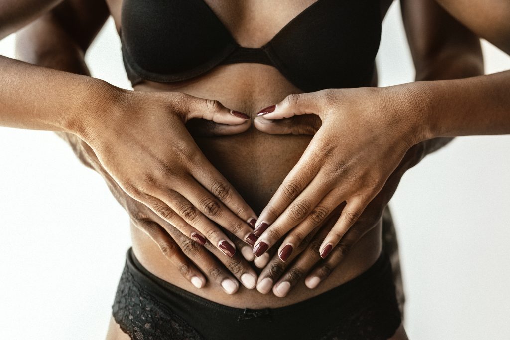 Manos entrelazadas sobre el abdomen simbolizando vínculo afectivo y salud íntima