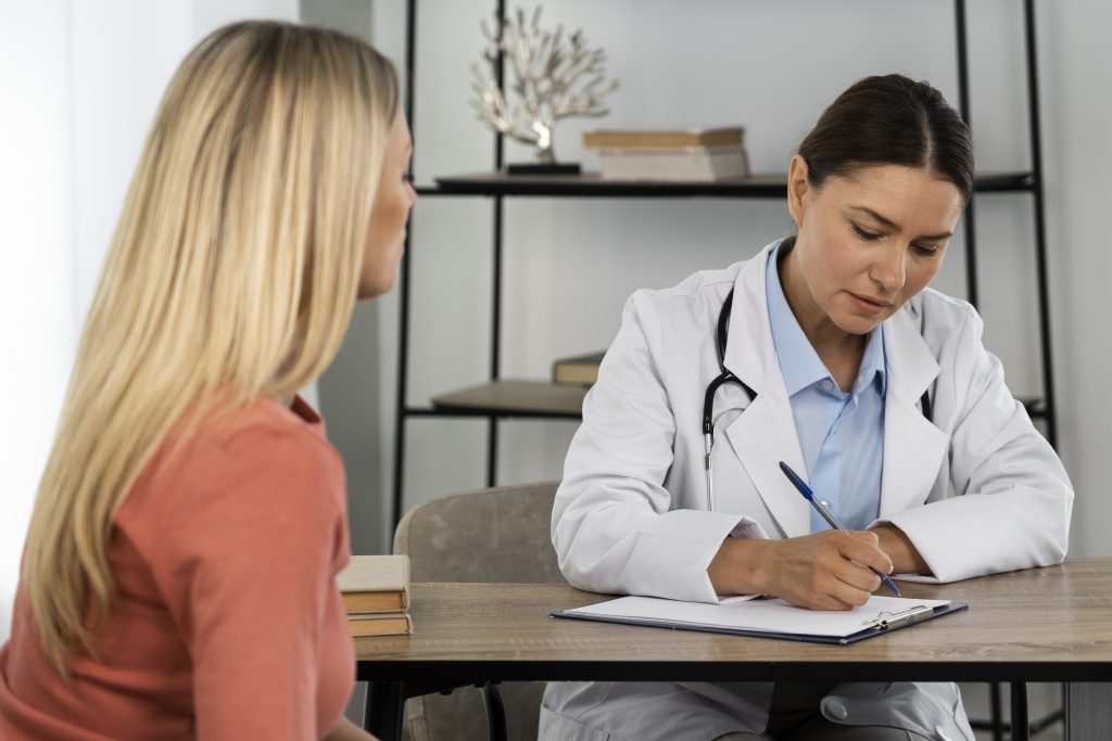 Mujer joven conversando con una doctora en una consulta médica