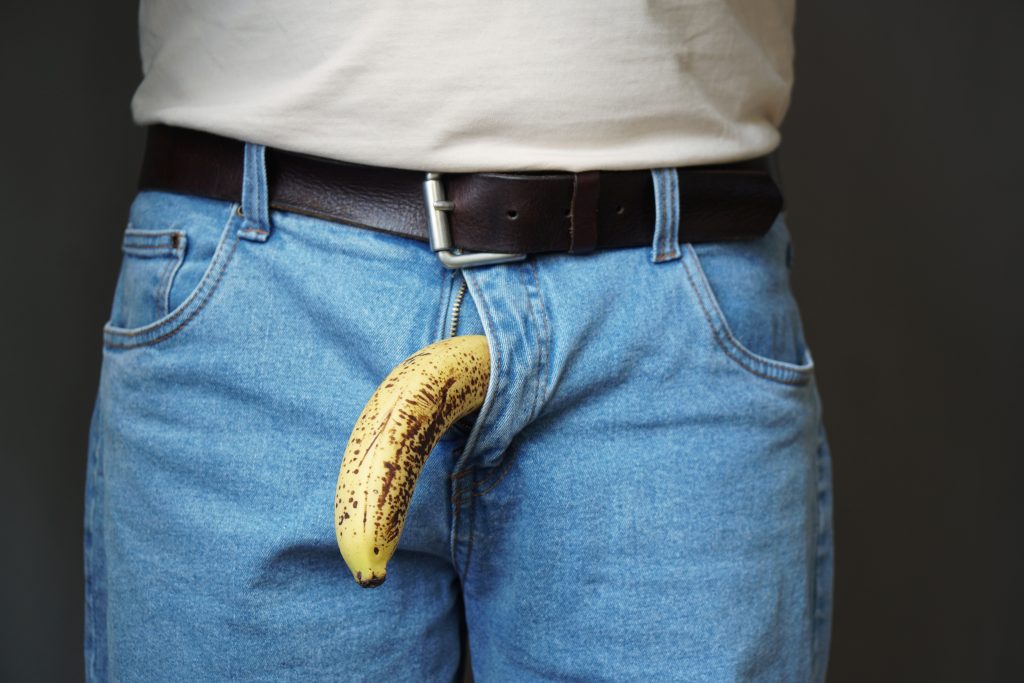 Hombre con plátano saliendo del pantalón, metáfora visual de la masturbación masculina y la salud sexual.